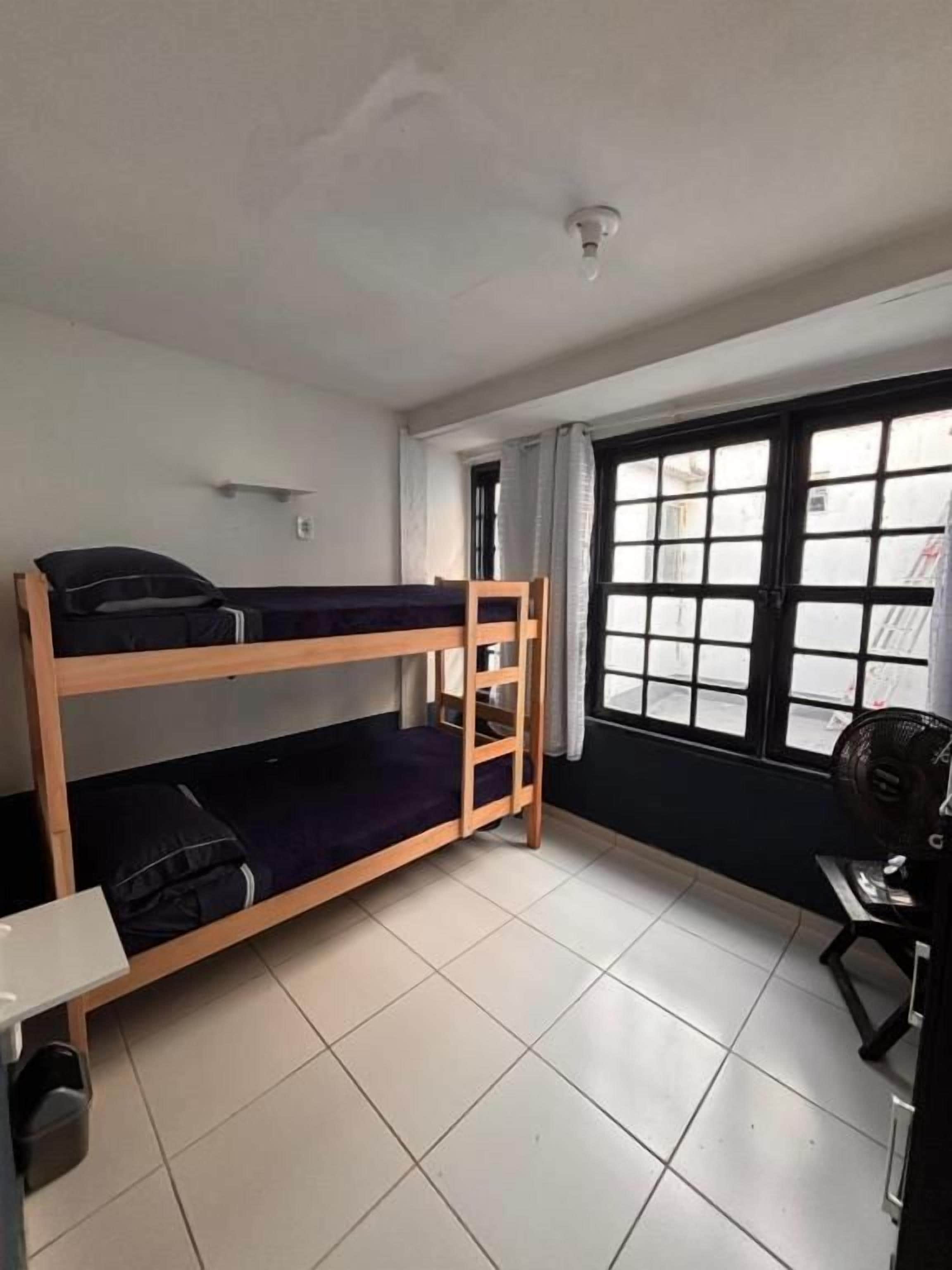 Habitación con literas, una ventana, un escritorio y una silla.