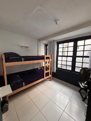 Habitación con literas, una ventana, un escritorio y una silla.