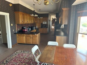 A kitchen with wooden cabinets, a dining table, and a patterned rug. - Massive 7-bedroom House in Charming Hayden (Hayden)