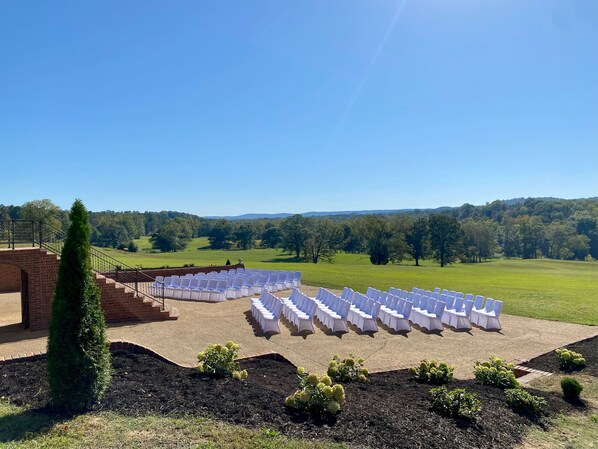 An outdoor seating area with rows of white chairs and a brick staircase leading up to a building. - Massive 7-bedroom House in Charming Hayden (Hayden)