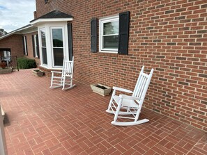 A brick house with two white rocking chairs on a brick patio. - Massive 7-bedroom House in Charming Hayden (Hayden)