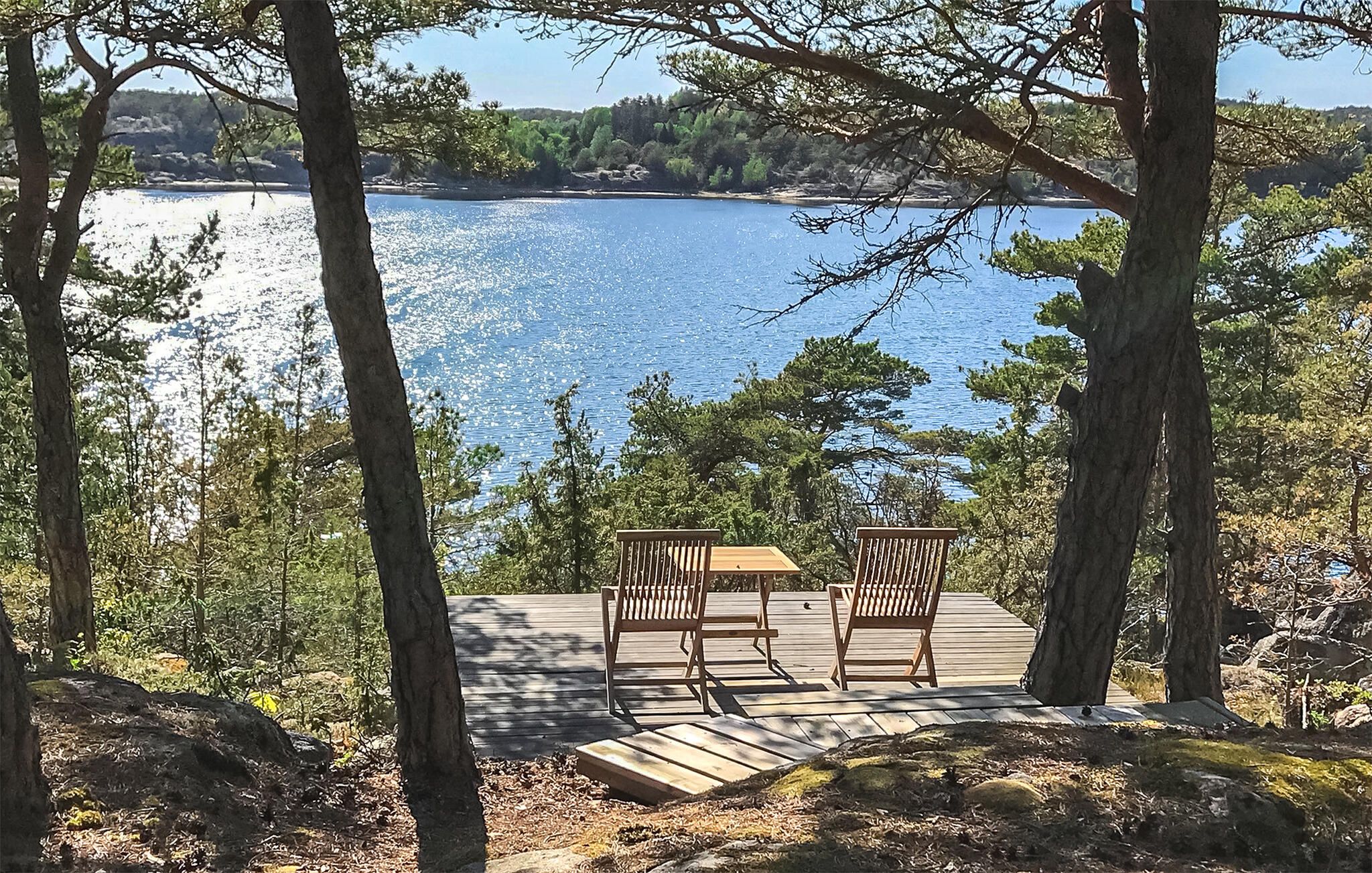 Une terrasse en bois avec deux chaises donnant sur une étendue d’eau.