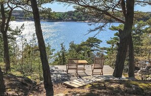 Une terrasse en bois avec deux chaises donnant sur une étendue d’eau.