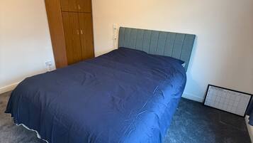 Quarto com cama, guarda-roupa e luminária na parede.