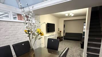 A modern dining area with a long table, black chairs, and a vase with flowers.