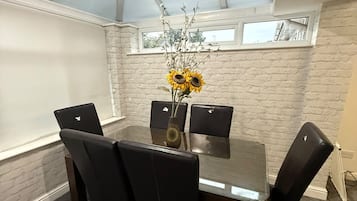 Une salle de conférence avec une table en verre, des chaises noires et un vase rempli de tournesols.