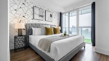 A modern bedroom with a large bed, a geometric wall design, and a city view.