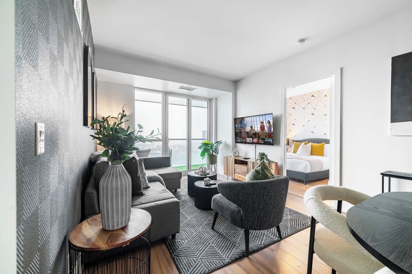 A modern living room with a sofa, armchairs, a coffee table, and a TV.