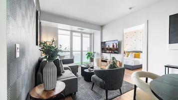 A modern living room with a sofa, armchairs, a coffee table, and a TV.