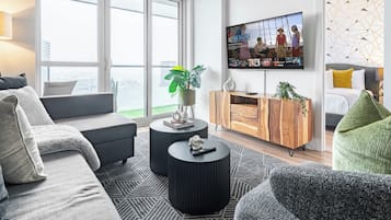 Un salon moderne doté d’un grand téléviseur, de sièges confortables et offrant une vue par la fenêtre.
