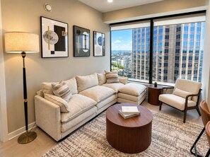 A modern living room with a sectional sofa, a round coffee table, and a floor lamp. - Birmingham Hideaway | 2BR + King (Birmingham)