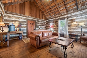 A log cabin interior with a leather sofa, wooden coffee table, and rustic decor. - Cabin w/King bed on Wine Trail, Walk to Wineries! (Fredericksburg)