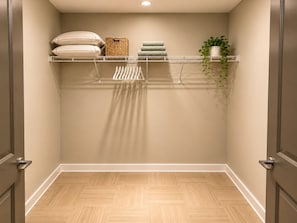 A walk-in closet with a wooden herringbone floor, a metal drying rack, and a potted plant. - Skyline Nook | 2BR Downtown Stay (Birmingham)