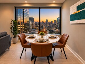 A dining area with a city view, a round table, and modern chairs. - Skyline Nook | 2BR Downtown Stay (Birmingham)
