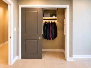 A closet with hanging clothes and a storage box. - Skyline King Stay | 2BR Downtown (Birmingham)
