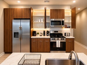 A modern kitchen with wooden cabinets, stainless steel appliances, and a marble countertop. - Skyline Escape | 3BR + King Bed (Birmingham)