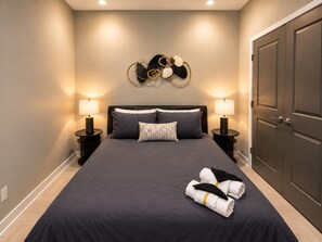 A hotel room with a large bed, two bedside tables, a wall-mounted decorative piece, and a wardrobe. - Skyline Escape | 3BR + King Bed (Birmingham)