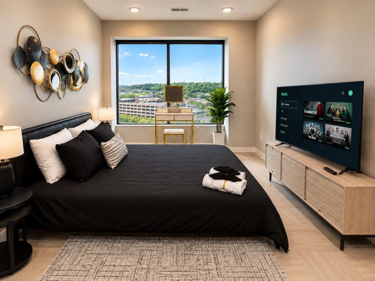 Un dormitorio moderno con una cama grande, televisor y vistas a la ciudad.