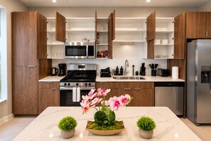 A modern kitchen with wooden cabinets, stainless steel appliances, and a marble countertop. - The Birmingham View | Spacious 2BR (Birmingham)