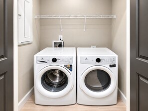 A laundry room with two front-loading washing machines and a drying rack above. - The City Glow | Spacious 2BR | 2 Queens (Birmingham)