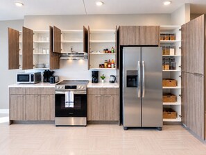 Une cuisine moderne dotée d’appareils électroménagers intégrés, de meubles en bois et d’étagères ouvertes pour le rangement.