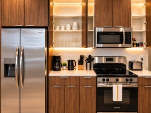 A modern kitchen with stainless steel appliances, wooden cabinets, and a built-in microwave. - Downtown View Retreat | 3BR | 2 Kings (Birmingham)
