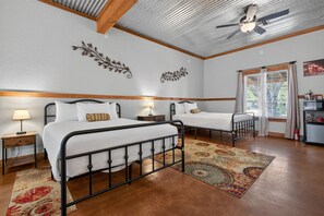 Ein Schlafzimmer mit zwei Betten, einem Deckenventilator, Wanddekoration und Blick durch ein Fenster.