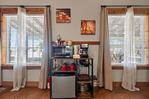 Eine Küchenzeile mit Kühlschrank, Mikrowelle, Kaffeemaschine und Tassen.