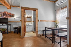 Ein gemütlicher, kompakter Wohnraum mit Küchenzeile, Essbereich und Fernseher.