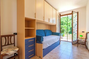 A room with a bed, a desk, and a chair. There is a sliding glass door leading to a garden. - Kedimore - GoldenHouse Lazise (Lazise)