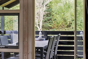 Un espace extérieur aménagé avec une table et des chaises, une bouteille et un vase.