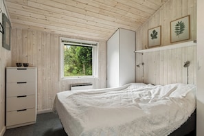 Une chambre à coucher avec un lit, une commode, une fenêtre et un radiateur.