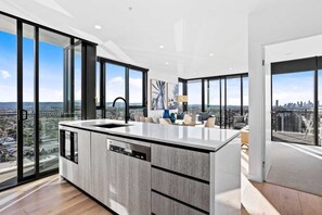 Una cocina moderna con una isla grande, lavavajillas y vistas a la ciudad a través de amplios ventanales.