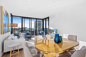Ein modernes Wohnzimmer mit einem Glastisch, Sofas und Blick auf die Stadt.