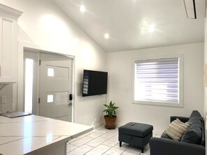 Un salon moderne avec un téléviseur à écran plat, un canapé, une table basse et une plante en pot.