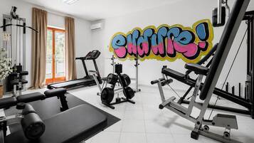 Un gimnasio con equipo de ejercicio, una cinta de correr y una pared con un diseño de grafiti colorido.