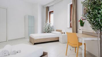 Una habitación de hotel moderna con cama, escritorio, silla, armario y una planta en maceta.
