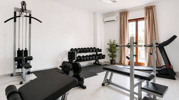 A gym with a bench press, dumbbells, a treadmill, and a squat rack.