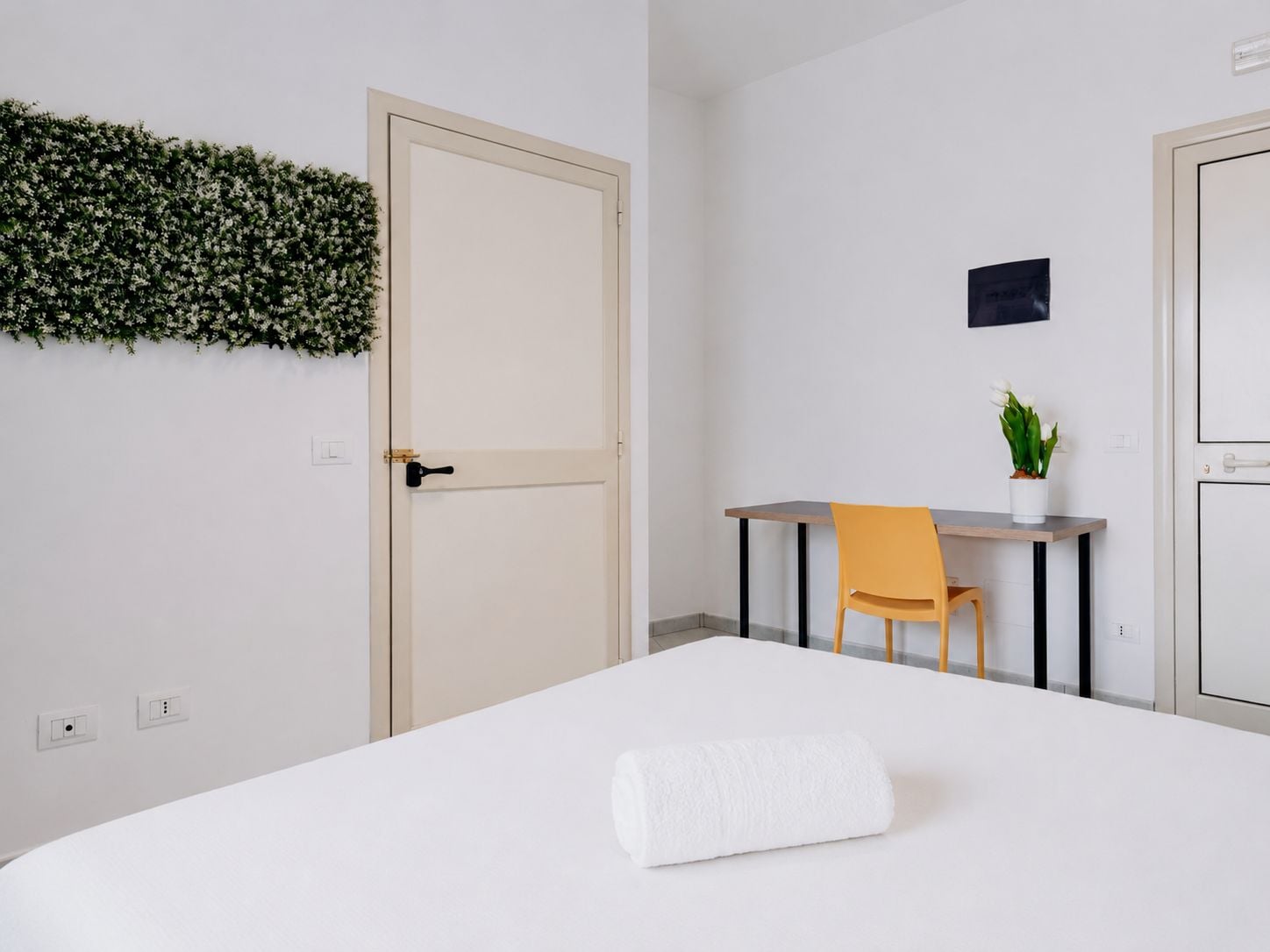 Une chambre à coucher avec un lit, un bureau, une chaise et une plante en pot.