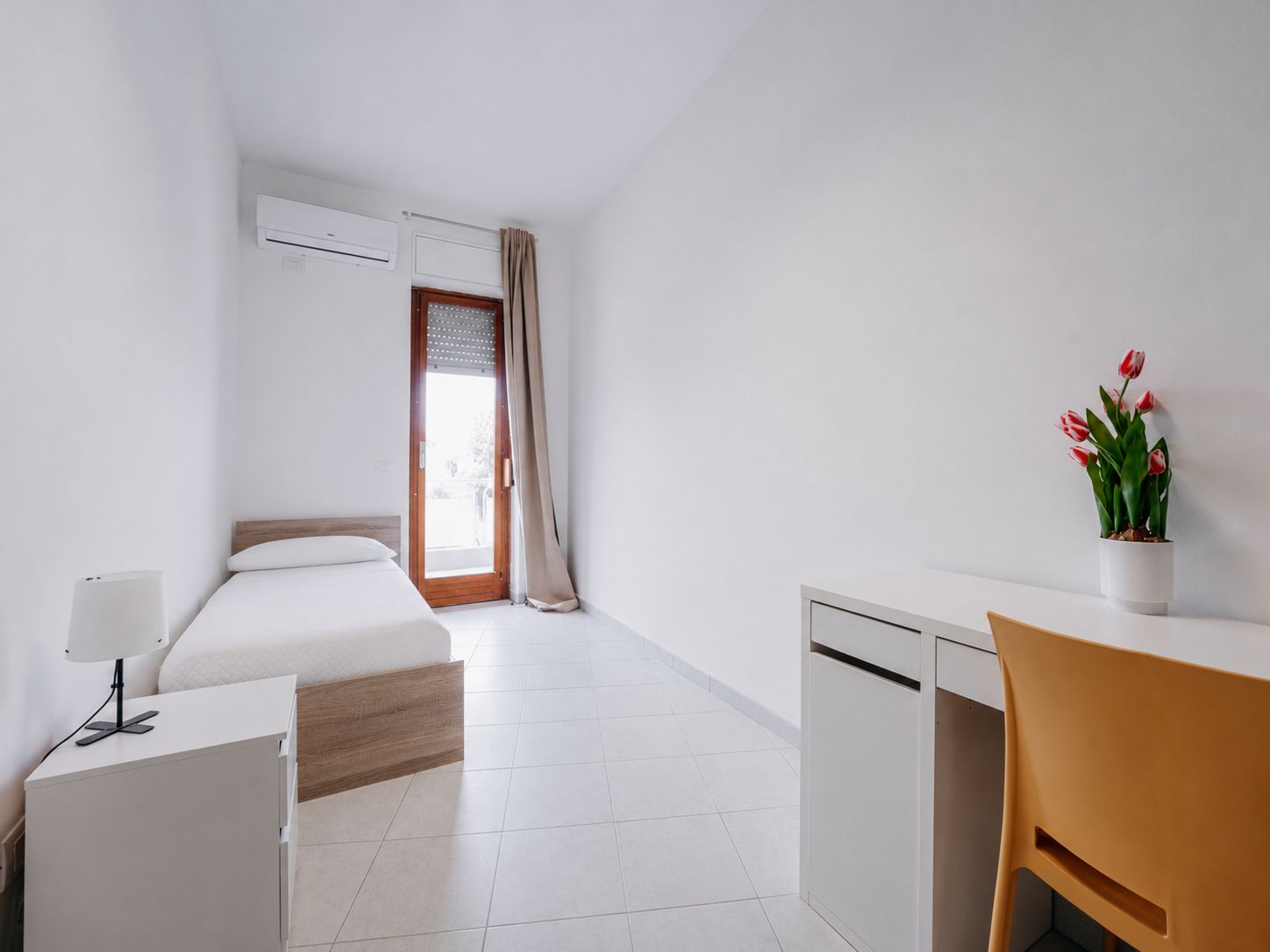 Une chambre d’hôtel équipée d’un lit, d’un bureau, d’une chaise, d’une plante en pot et d’un appareil de climatisation.