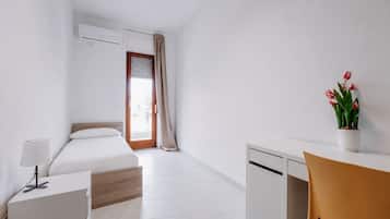 Une chambre d’hôtel équipée d’un lit, d’un bureau, d’une chaise, d’une plante en pot et d’un appareil de climatisation.