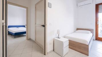 A hotel room with a bed, bedside table, and an air conditioning unit.