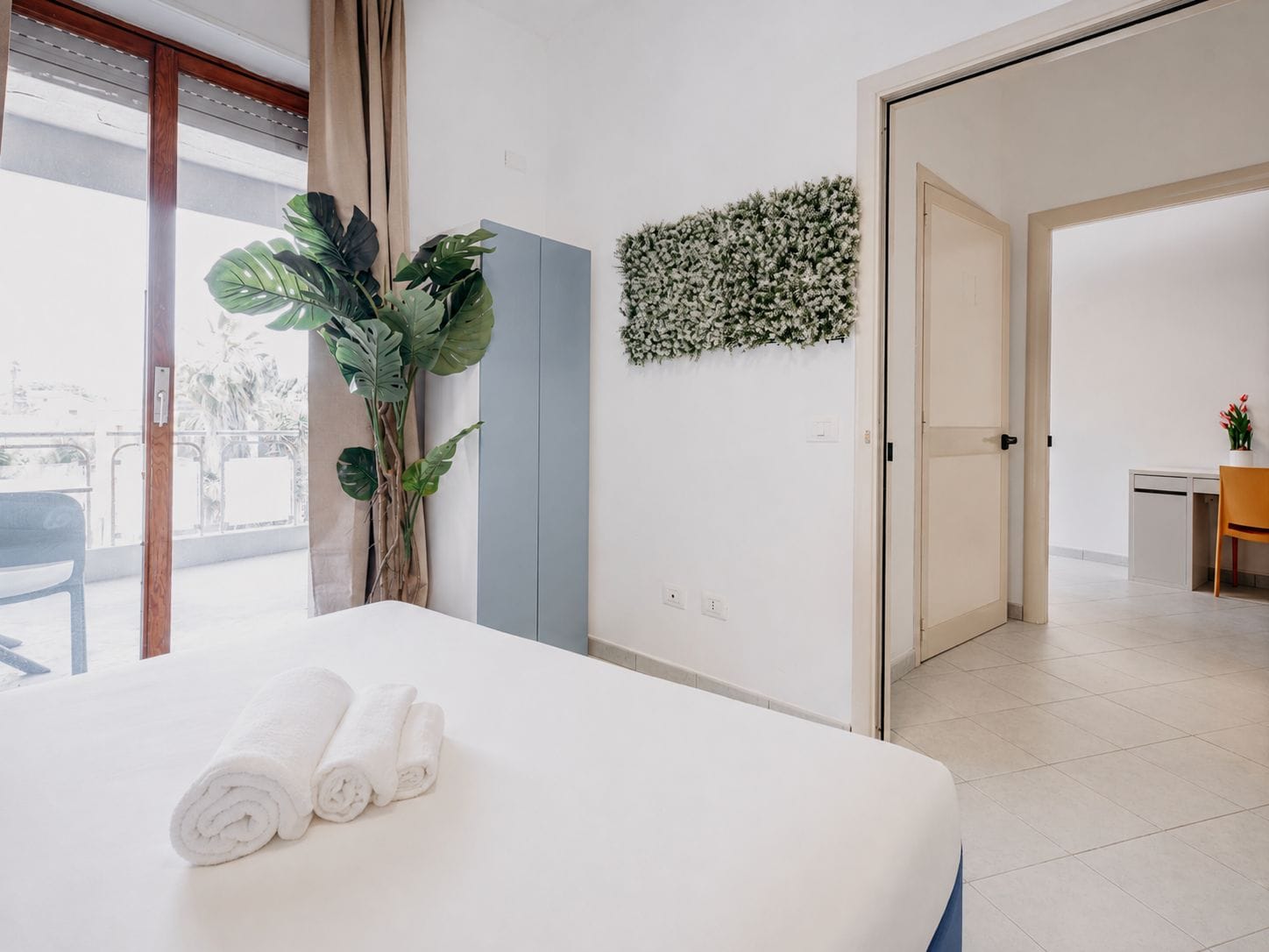 Una habitación de hotel con cama, una planta en maceta, un escritorio y vistas al exterior.