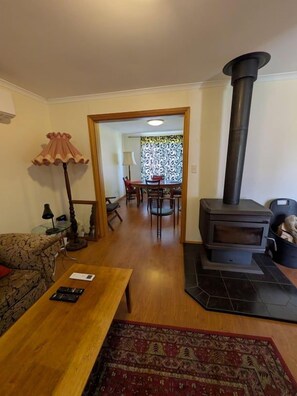 En stue med sofa, sofabord, pejs og et spiseområde med stole og bord.