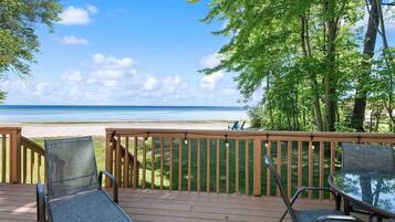 A deck with outdoor seating overlooking a beach.