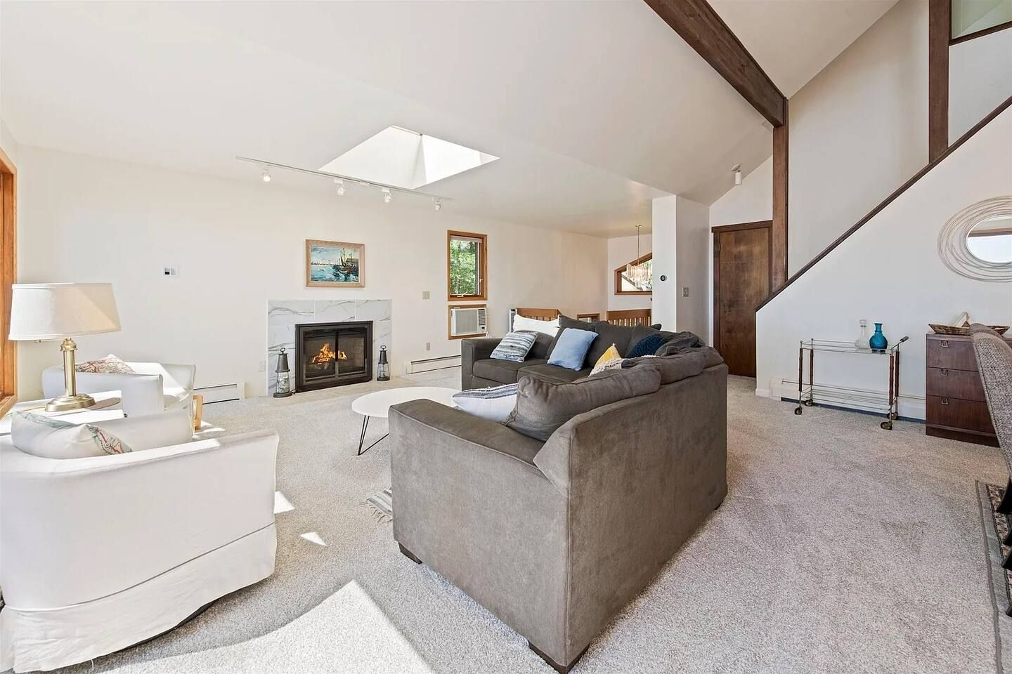 A modern living room with a fireplace, a sofa, a coffee table, and a staircase.