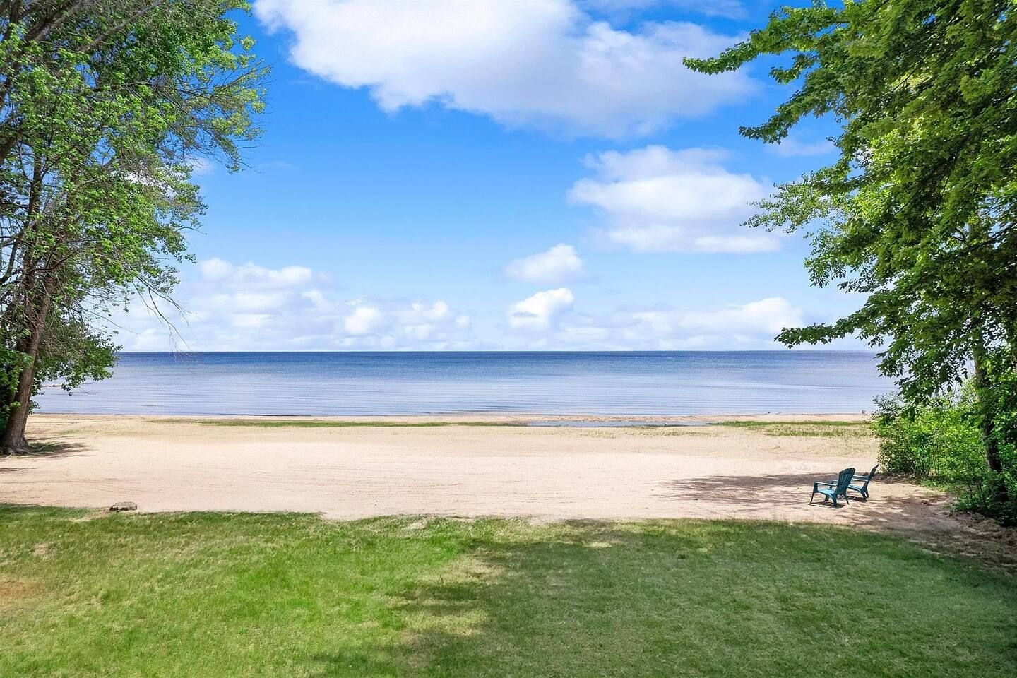 Une plage avec un ciel dégagé, un rivage sablonneux et une seule chaise verte.