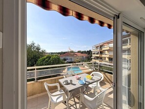 Ein Balkon mit Tisch und Stühlen, mit Blick auf einen Swimmingpool und eine Wohngegend.