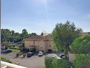Ein Gebäude mit Parkplatz und Baum im Vordergrund.