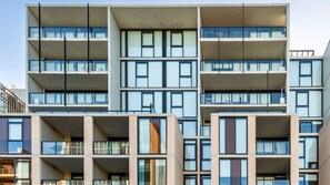 Ein mehrgeschossiges Gebäude mit zeitgemäßem architektonischen Design, mit Balkonen und großen Fenstern.